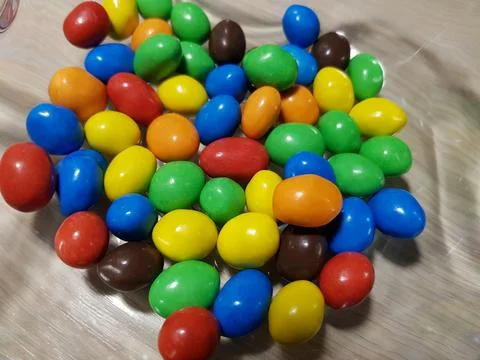 Multicolored chocolate-covered nuts in a transparent plate Stock Photos