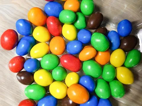 Multicolored chocolate-covered nuts in a transparent plate Stock Photos