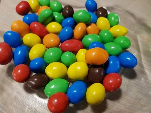 Multicolored chocolate-covered nuts in a transparent plate Stock Photos