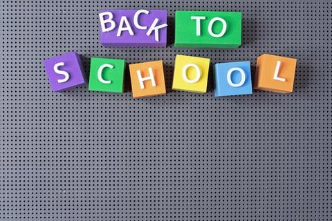 Multicolored cubes with the inscription "Back to school" on a gray background. Stock Photos