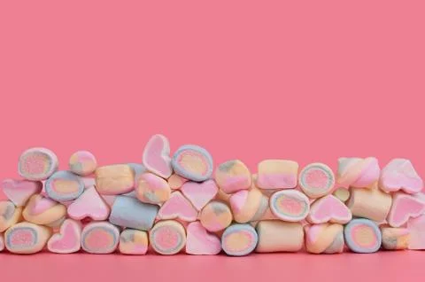Multicolored diverse marshmallows in several rows on a pink background 스톡 사진