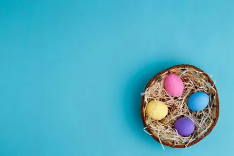 Multicolored Easter eggs in basket, flat lay with copy space Stock Photos