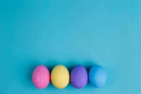 Multicolored Easter eggs on blue background, flat lay with copy Stock Photos