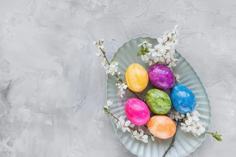 Multicolored Easter eggs on plate and spring white cherry blossom flowers on Stock Photos
