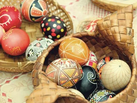 Multicolored easter eggs in straw pot. Stock Photos