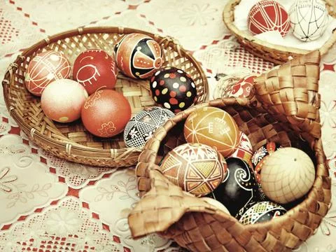 Multicolored easter eggs in straw pots on a table.Toned image. Stock Photos