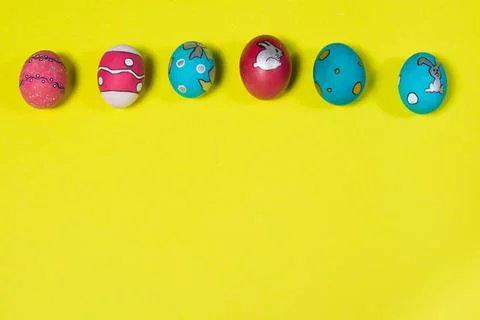 Multicolored Easter eggs on a yellow background with place for text. Stock Photos