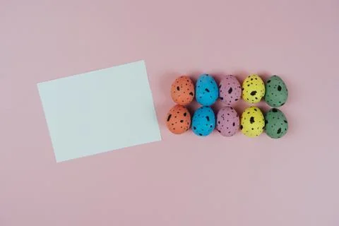 Multicolored Easter quail eggs and blank greeting card isolated on pink Stock Photos