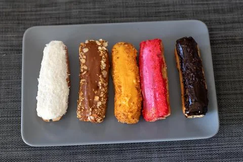 Multicolored eclair pastries on plate top view Stock Photos
