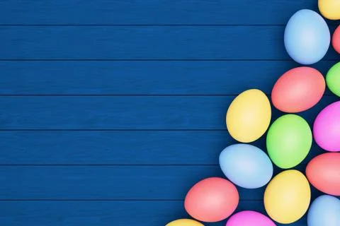 Multicolored eggs on a blue wooden table, happy Easter concept, copy space. Stock Illustration