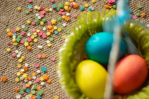 Multicolored eggs in easter festive basket on canvas napkin. Stock Photos