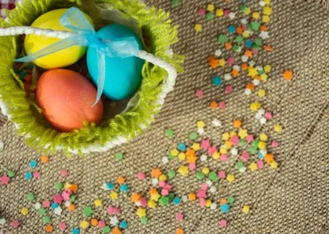 Multicolored eggs in easter festive basket on canvas napkin. Stock Photos