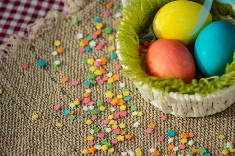 Multicolored eggs in easter festive basket on canvas napkin. Stock Photos