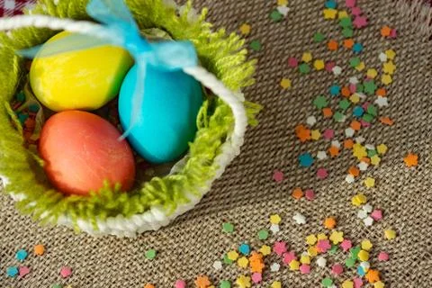 Multicolored eggs in easter festive basket on canvas napkin. Stock Photos