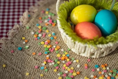 Multicolored eggs in easter festive basket on canvas napkin. Stock Photos