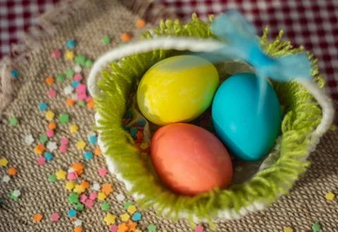 Multicolored eggs in easter festive basket on canvas napkin. Stock Photos