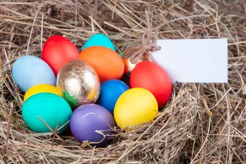 Multicolored eggs with a note in the hay. Mock up, concept easter. Stock Photos