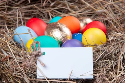 Multicolored eggs with a note in the hay. Mock up, concept easter. Stock Photos