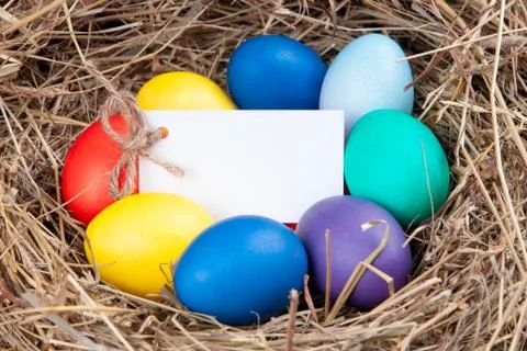 Multicolored eggs with a note in the hay. Mock up, concept easter. Stock Photos