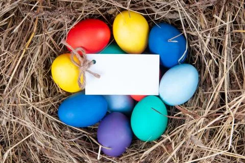 Multicolored eggs with a note in the hay. Mock up, concept easter. Stock Photos