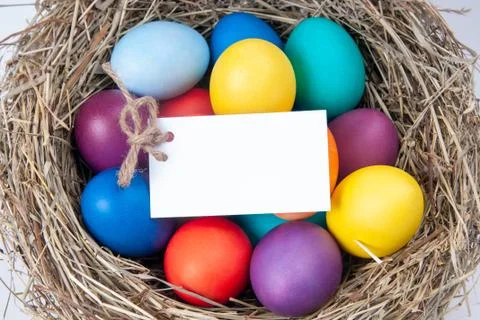 Multicolored eggs with a note in the hay. Mock up, concept easter. Stock Photos