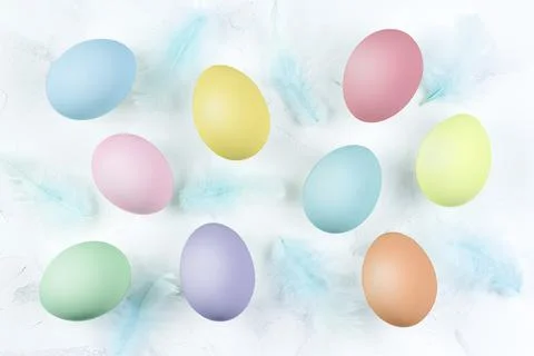 Multicolored eggs on a white textured background and blue feathers. Foto stock