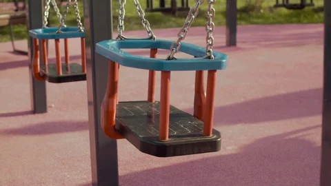 Multicolored empty swings swing in the wind, slow motion. Empty swings in the Stock Footage 75737263