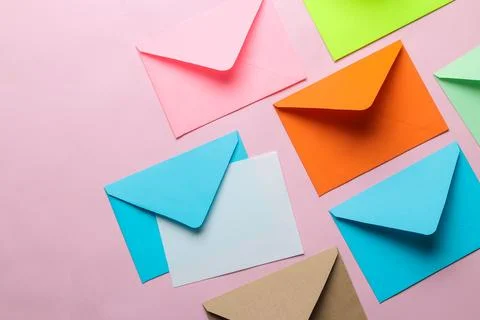 Multicolored envelope with blank for text on a bright trendy pink background. Stock Photos