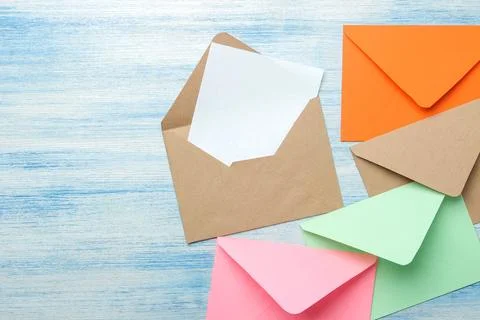 Multicolored envelopes with a blank for the text on a blue wooden table. top Stock Photos
