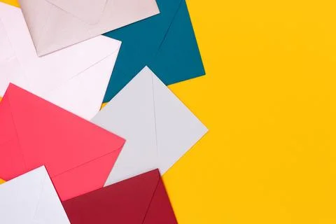 Multicolored envelopes scattered on a yellow background. Stock Photos
