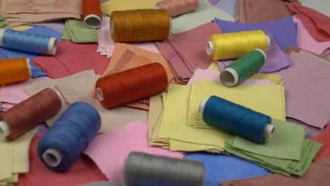 Multicolored fabrics for patchwork and spools of colored sewing threads on it Stock Footage 262261221