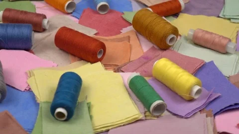 Multicolored fabrics for patchwork and spools of colored sewing threads on it Stock Footage 262261999