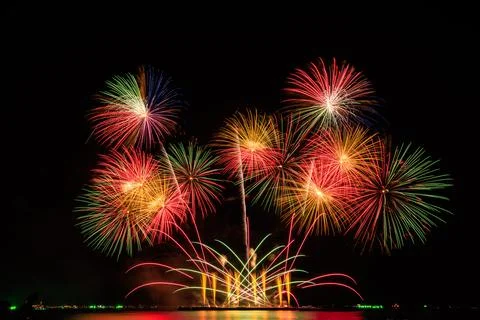 Multicolored Festive Fireworks Exploding Over Dark Water Night Scene 库存照片