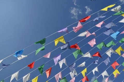 Multicolored flags on blue sky background and white clouds. Stock Photos