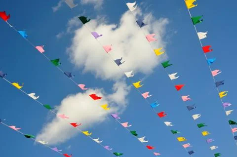 Multicolored flags on blue sky background and white clouds. Stock Photos