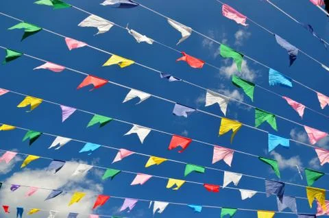 Multicolored flags on blue sky background and white clouds. Stock Photos