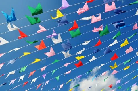 Multicolored flags on blue sky background and white clouds. Stock Photos