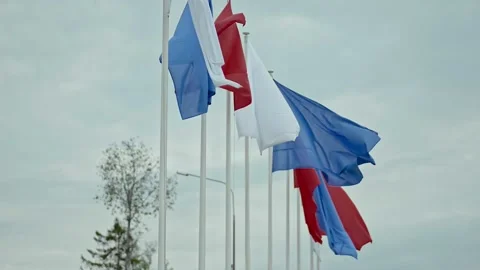 Multicolored flags fluttering in wind under blue sky in city in summe day. 스톡 동영상 157231752