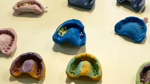 Multicolored frame workpiece dental dentures and plaster casts of teeth on the Video stock 73669421