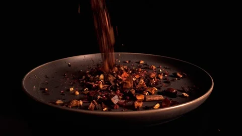 Multicolored fruit dry tea pour onto dark turning plate on black background Stock-Footage 125192637
