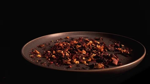 Multicolored fruit dry tea rotate onto dark turning plate on a black background Stock Footage 125192641