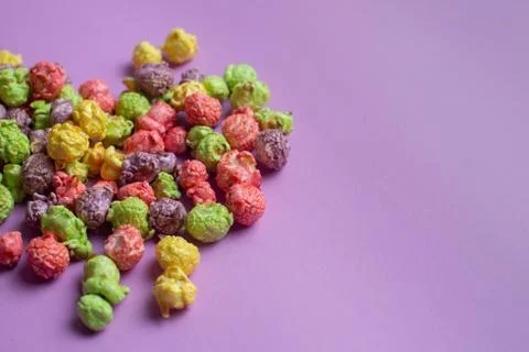 Multicolored fruit flavored popcorn on pink background. Candy coated popcorn. Stock Photos