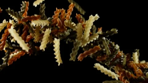 Multicolored fusilli pasta macaroni bouncing falling down on black background Stock Footage 105852510