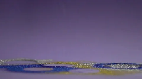 Multicolored glitter is deposited on the surface and blue-and-white background. Video stock 77581108