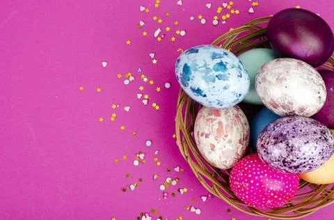 Multicolored handmade easter eggs and confetti on pink background. Minimal co Stock Photos