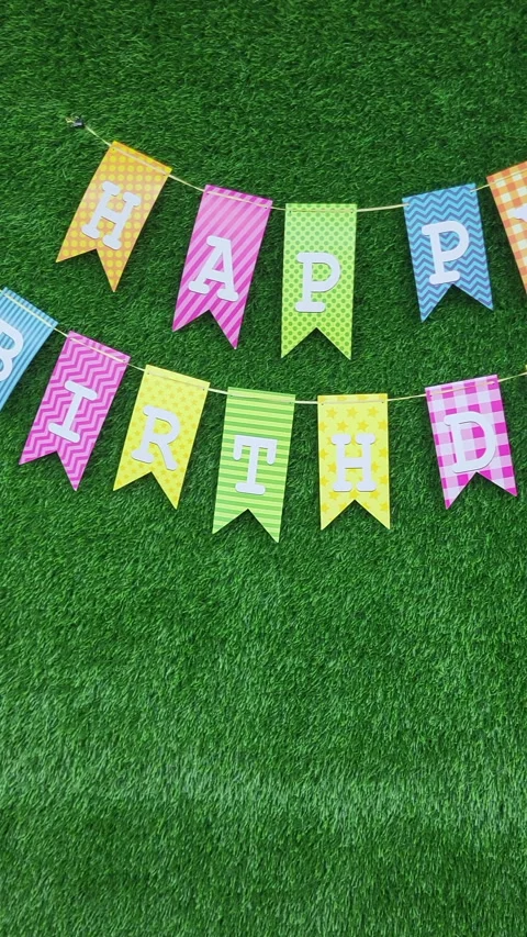 Multicolored ""Happy Birthday"" bunting with patterned flags hanging on green Stock Footage 297169644