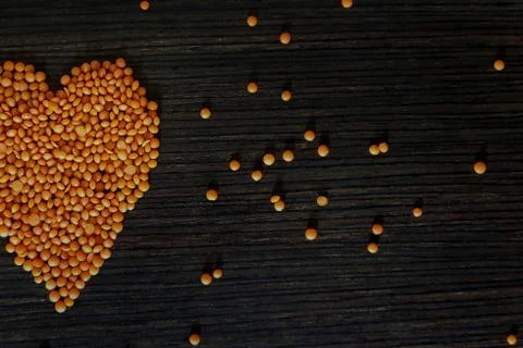 Multicolored heart frame made from a mixture of peas and lentils on a wooden Stock Photos