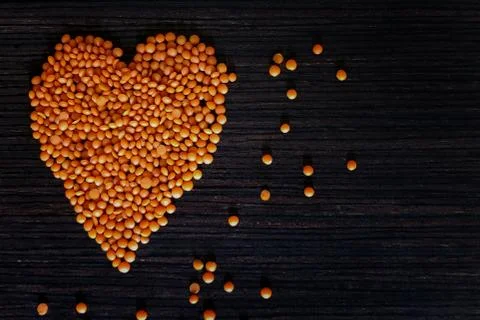 Multicolored heart frame made from a mixture of peas and lentils on a wooden Stock Photos