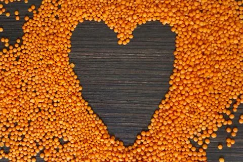 Multicolored heart frame made from a mixture of peas and lentils on a wooden Stock Photos