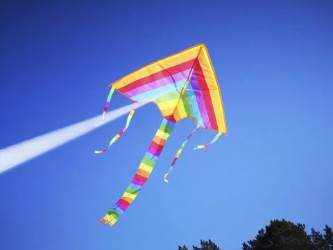Multicolored kite attached to white string against blue sky Stock Photos